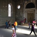 (Courtesy Photo) Children explore the site-specific art installation “Hello Goodbye” created in Samorin, Slovakia by JP artist Alison Safford following its March 22 opening. The work consists of porcelain hands on rods suspended from wires inside the At Home Gallery—a former synagogue—as an expression of reaching across symbolic spaces. Safford, who traveled to the Central European nation to install the piece, met the gallery owners at last year’s Boston Transcultural Exchange Conference.