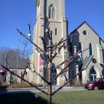 (Gazette Photo by John Ruch) A “Jesse Tree” representing the Christian tradition of Advent and decorated by community members stands outside the First Baptist Church in Jamaica Plain at 633 Centre St. last week. The metal structure was created by JP’s Stonybrook Fine Arts.