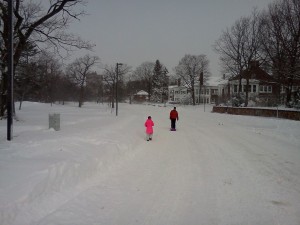 A man and a little girl tow a sled up the empty Jamaicaway on Feb. 9. (Gazette Photo by John Ruch)