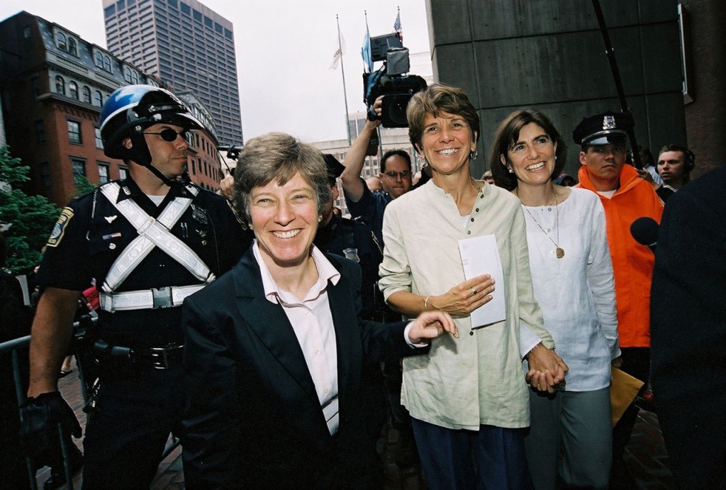 (Photo by Ellen Shub) Hillary and Julie Goodridge, then JP residents, hold hands after leaving Boston City Hall with the first same-sex marriage license issued in Boston, joined by attorney Mary Bonauto of Gay and Lesbian Advocates and Defenders, on May 17, 2004. The historic moment was captured in this photograph by Newton’s Ellen Shub, whose exhibit “Women Making History: Portraits and Protests” is showing at the Connolly Branch Library in Hyde Square.
