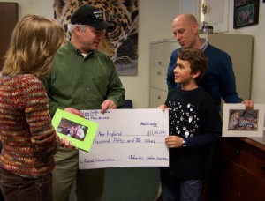 (Courtesy Photo) Adam Crellin-Sazama presents John Linehan, Zoo New England president and CEO, with a check for $1,050 last week as parents Jenny Sazama and Tim Crellin look on. The photo has been slightly altered to obscure the family’s address for privacy reasons.